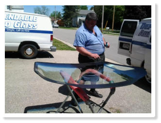 Mike prepping windshield glass on a mobile stand next to the van